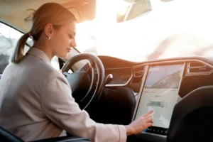 A imagem mostra uma mulher mexendo no painel de um carro elétrico, representando alugar Tesla.